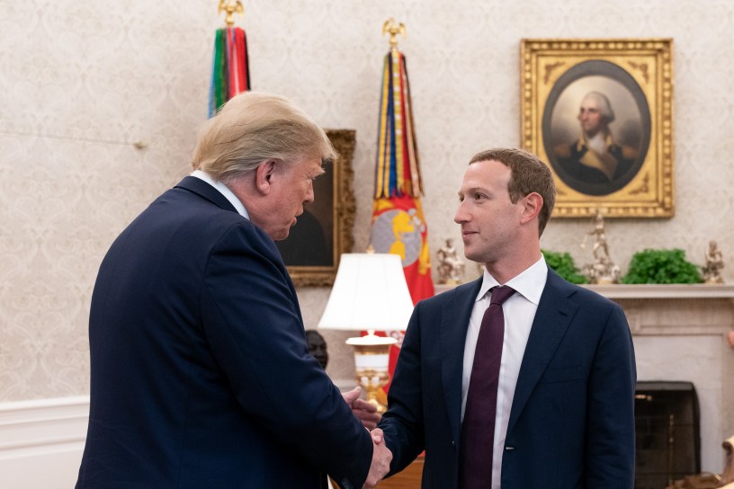 Donald Trump and Mark Zuckerberg shake hands in the Oval Office. A portrait of George Washington and military flags are visible in the background.
