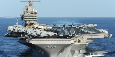 USS Abraham Lincoln (CVN-72) underway at sea, viewed from ahead with aircraft and flight-deck crews visible on the carrier deck.